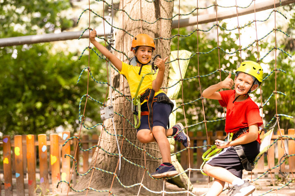Милі діти. Хлопчик і дівчинка скелелазіння в будівлі мотузкового ігрового майданчика в парку пригод
 - Фото, зображення