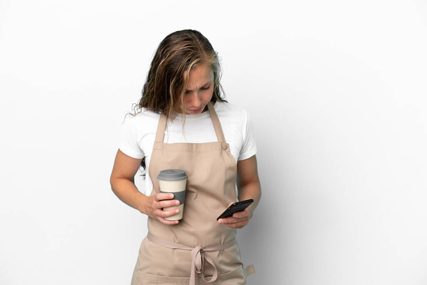 Restaurante camarero mujer caucásica aislada sobre fondo blanco sosteniendo café para llevar y un móvil - Foto, Imagen