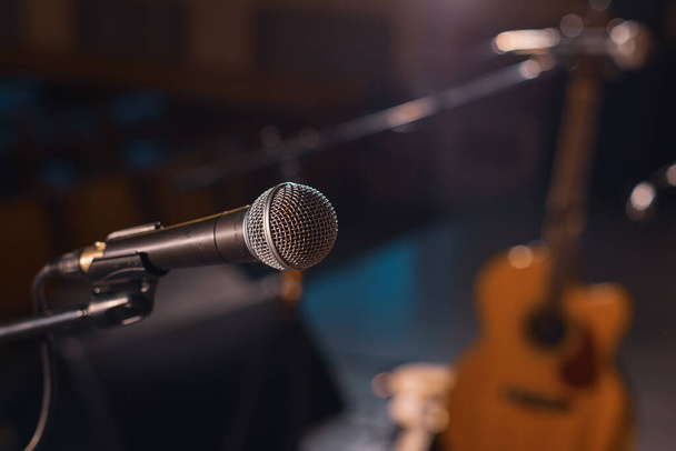 micrófono en el fondo de un escenario vacío, la guitarra en el fondo está borrosa fuera de foco. esperando el concierto - Foto, imagen