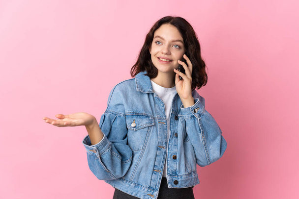 Teini Ukrainan tyttö eristetty vaaleanpunainen tausta pitää keskustelun matkapuhelimen kanssa jonkun - Valokuva, kuva