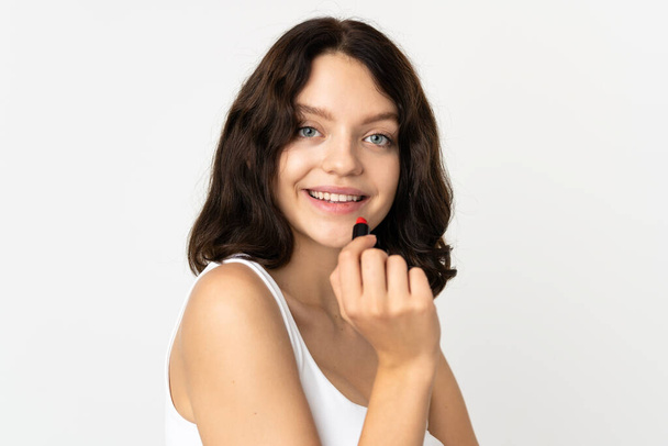 Teenager Ukrainian girl isolated on white background holding red lipstick - Photo, Image