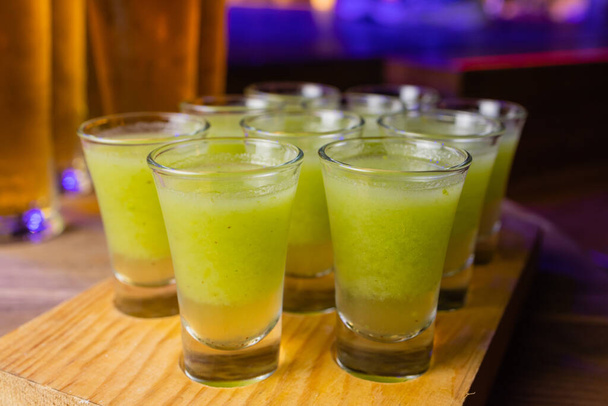Green liquid in shot glasses standing on the counter. - Фото, зображення