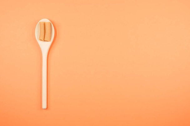 A top view shot of rigatoni on a spoon on an orange surface with free space for text - Фото, изображение