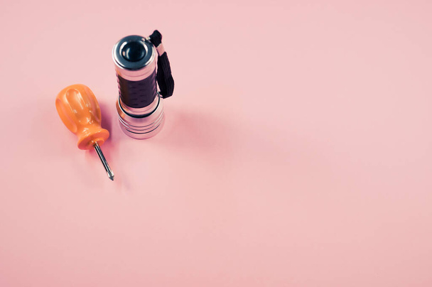 A closeup shot of a small fleshlight and mini screwdriver on pink background - Foto, Imagen