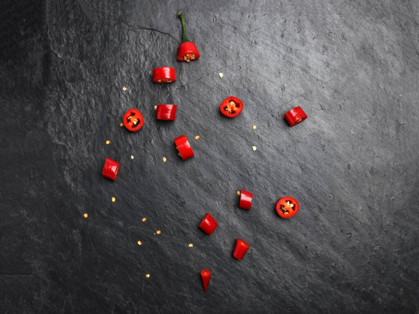 Красный острый перец чили на темном черном грубом фоне из камня - Фото, изображение