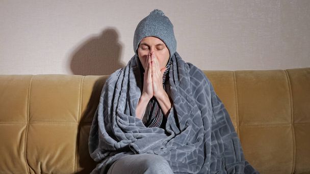 Upset frozen man trembles with cold sitting on modern sofa - Foto, Imagen