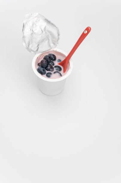 A vertical shot of a cup of yogurt with fresh berries on a white surface - Foto, immagini