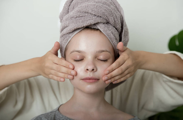 Little girl enjoys facial massage cream mask on their faces. Little girl and young woman enjoy spa procedures. SPA and wellness. - Foto, afbeelding