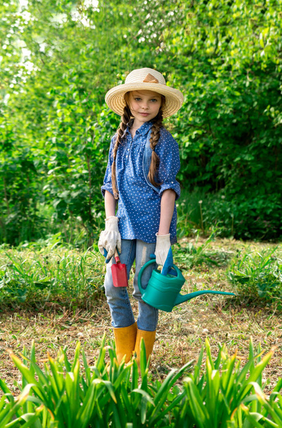 Little cute girl watering trees and flowers in the family garden at a summer day. Kid helping at the farm. - Photo, Image