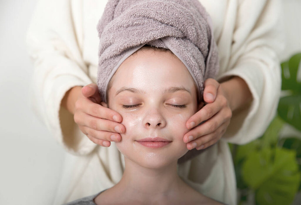 Little girl enjoys facial massage cream mask on their faces. Little girl and young woman enjoy spa procedures. SPA and wellness. - Foto, Imagem