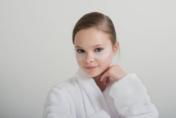 Little girl playing with cosmetic SPA mask and eye panda patches mask on her faces. Little girl enjoy home spa treatments. SPA and wellness. - Φωτογραφία, εικόνα
