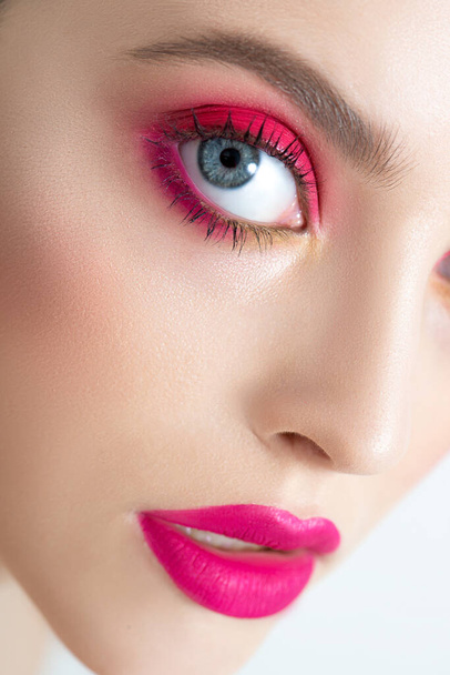Closeup of beautiful young woman's face with perfect skin, long eyelashes and bright vivid pink make up. Portrait of fashion beauty model with colorful professional makeup. Micro, selective focus. - Фото, изображение