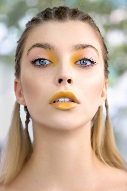 Portrait of beauty model with yellow creative makeup. Beautiful young  woman with fresh clean perfect skin and professional make up. Close up, Selective focus. - Fotografie, Obrázek
