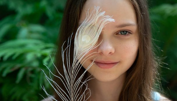Little cute girl with big white feather in hands. Child or teen skin care concept. Natural cosmetics. - Fotó, kép