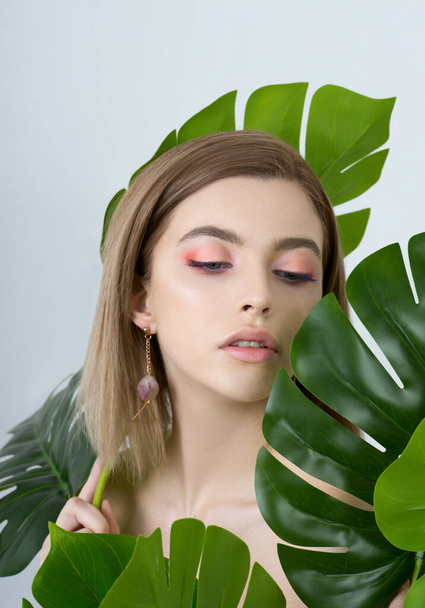 Beautiful young woman with perfect skin and natural make up posing front of plant tropical green leaves background. Teen model are of her face and body. SPA, wellness, bodycare and skincare. - Foto, Bild