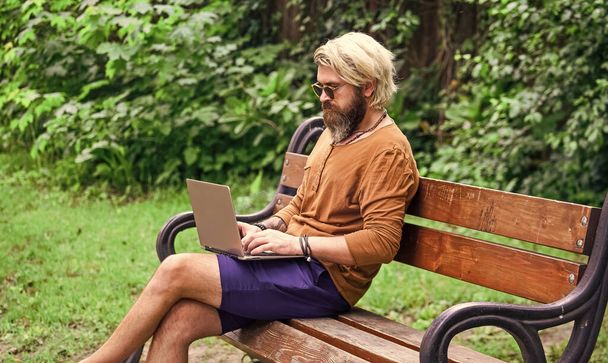 bearded man sit on bench with laptop. online distant education. hipster inspired to work in park. agile business. mature student working on computer. go shopping on cyber monday - Zdjęcie, obraz
