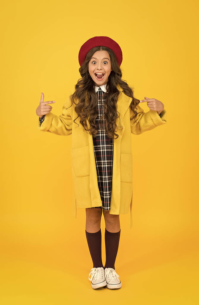 she is so surprised. little girl in coat going to school. education concept. school and fashion. child in pupil uniform. kid in french beret on yellow background. stylish teen college student - Foto, Imagem