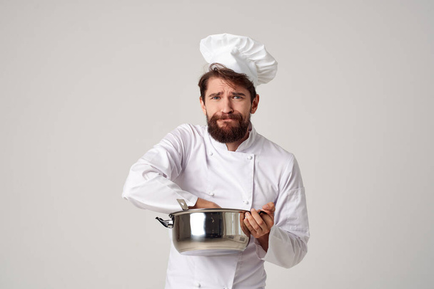 een man in koks kleding met een steelpan in zijn handen keukenwerk koken - Foto, afbeelding