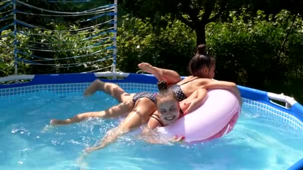 Chicas felices se divierten flotando juntos en el anillo de natación en la piscina al aire libre, verano - Metraje, vídeo
