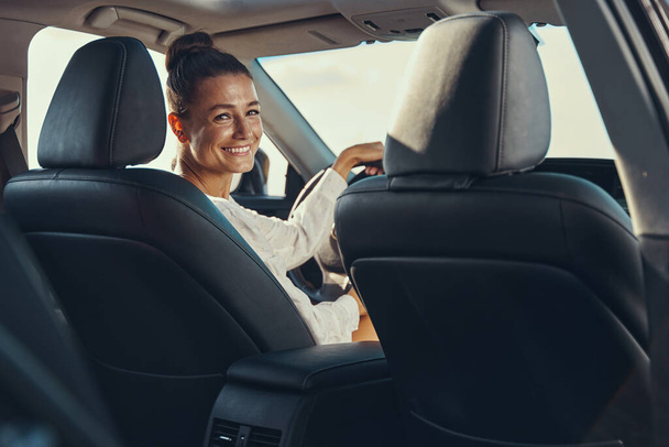 Excited female turning to rear seat while driving - Photo, Image