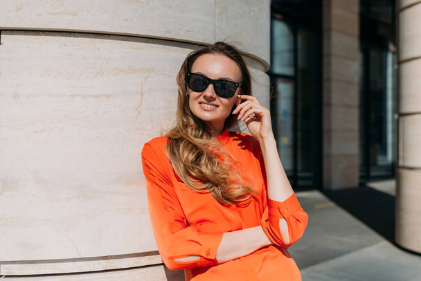 Женщина, 30 лет, стильная модель, позирует на камеру в очках в центре города - Фото, изображение