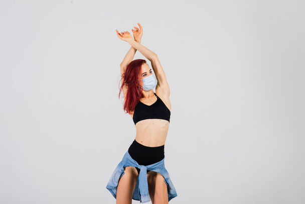 Γυναίκα χορεύτρια στο στυλ της ταινίας πλαστικό και πόλο χορού με μάσκα προσώπου στο φως φόντο. - Φωτογραφία, εικόνα