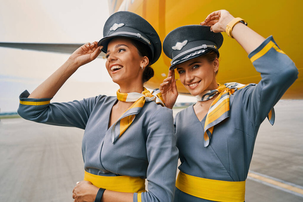 Radosne stewardessy w mundurach przez wylądowany samolot - Zdjęcie, obraz