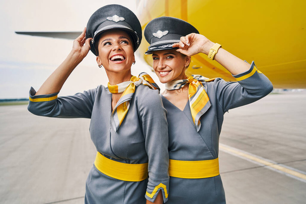 Auxiliares de vuelo con gorras de piloto en el aeródromo - Foto, imagen