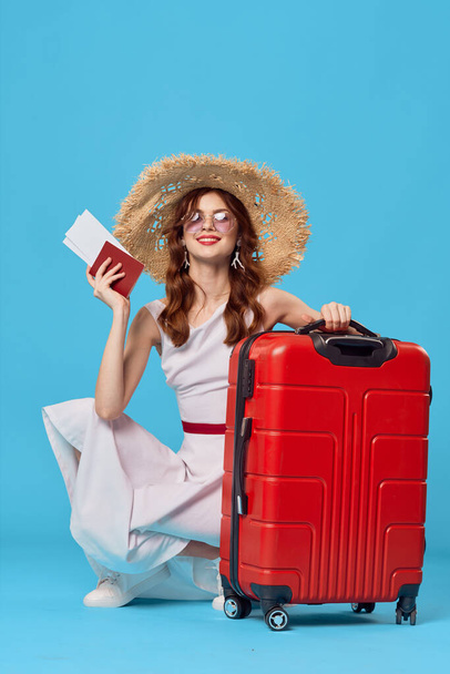 γυναίκα με κόκκινη βαλίτσα κάθεται στο πάτωμα μπλε φόντο ταξίδια διακοπές - Φωτογραφία, εικόνα