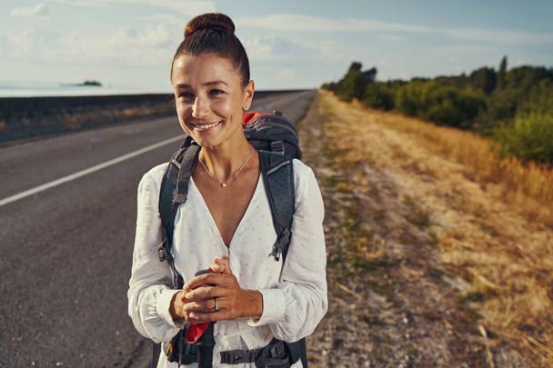 Caucasian female checking the road for cars during hiking trip - 写真・画像