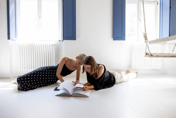Lesbian couple reading book at home - Photo, Image