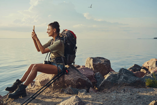 Female traveller on rock taking picture of sunset - Valokuva, kuva