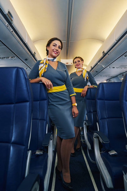 Stylowe stewardesy pozujące do kamery przed startem - Zdjęcie, obraz