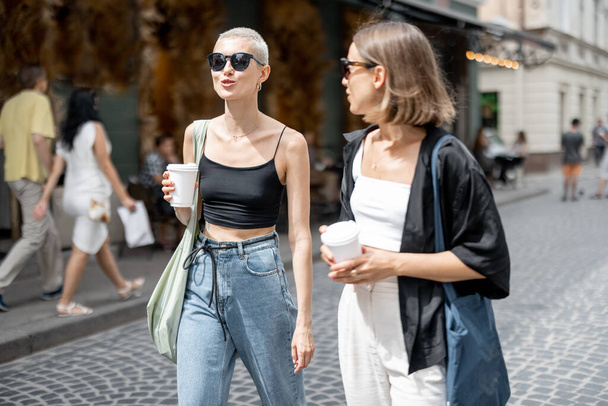 Stylish female couple standing together with a coffee cups outdoors - Photo, image
