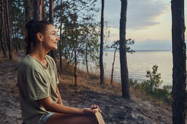 Female enjoying a lake view while holding a log - Fotografie, Obrázek