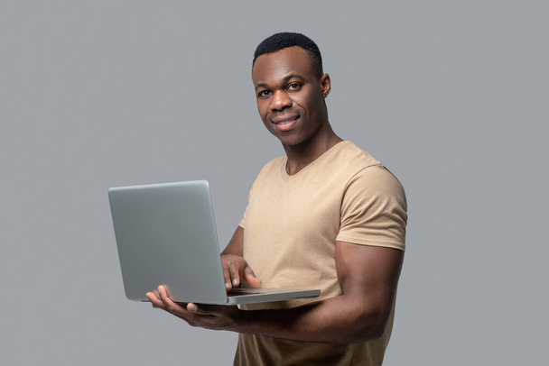 Dark-skinned young man with a laptop in hands - Φωτογραφία, εικόνα
