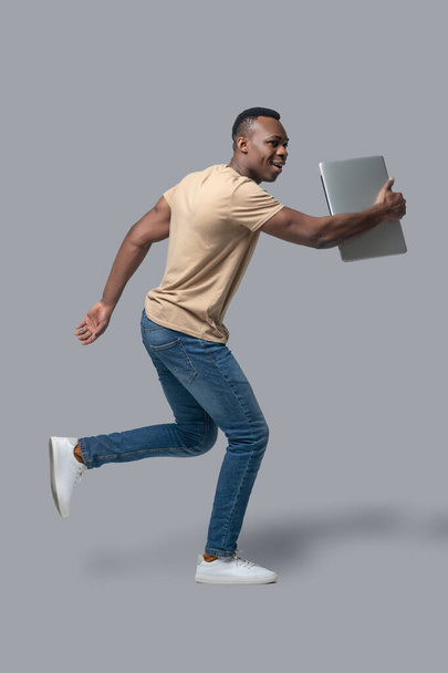 Dark-skinned young man with a laptop in hands - Foto, Imagen