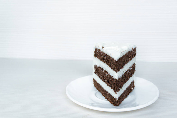 The chocolate sponge cake with butter cream is located on the right. White background. - Фото, зображення