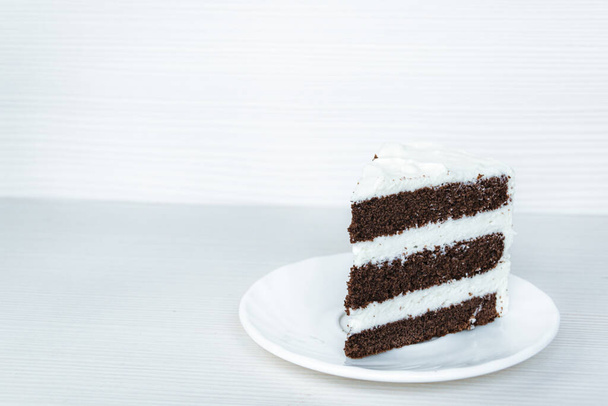 A slice of chocolate sponge cake with butter cream is located on the right. White background. - Φωτογραφία, εικόνα
