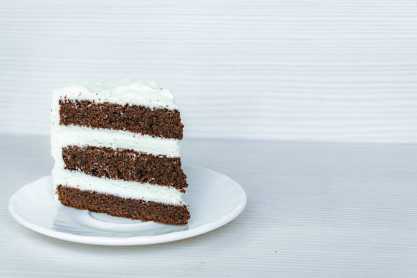 The slice of chocolate sponge cake with butter cream is located on the left. White background. - Foto, Imagen