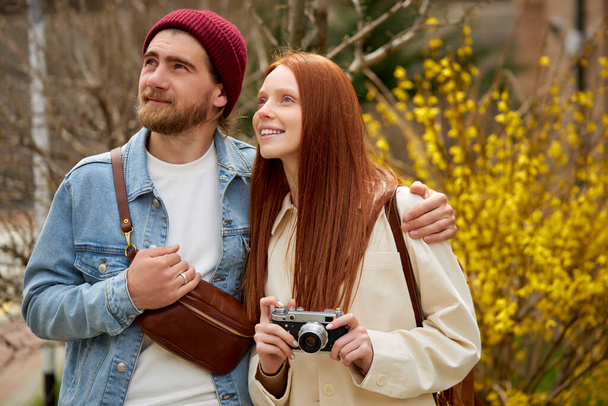 couple travelers in casual outfit walk in spring or autumn forest, with retro camera - Foto, Imagem