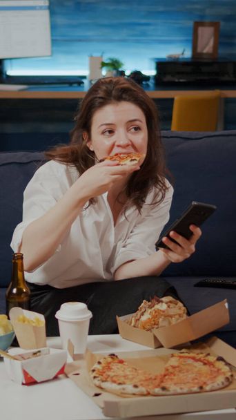Бізнес-леді, використовуючи смартфон під час їжі скибочки піци
 - Фото, зображення
