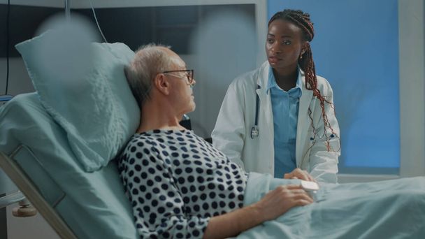 African american doctor talking to elder sick patient - Fotoğraf, Görsel