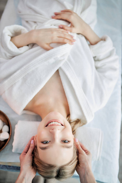 Young woman enjoying massage in spa salon. Face massage by female masseur. - Foto, Imagem