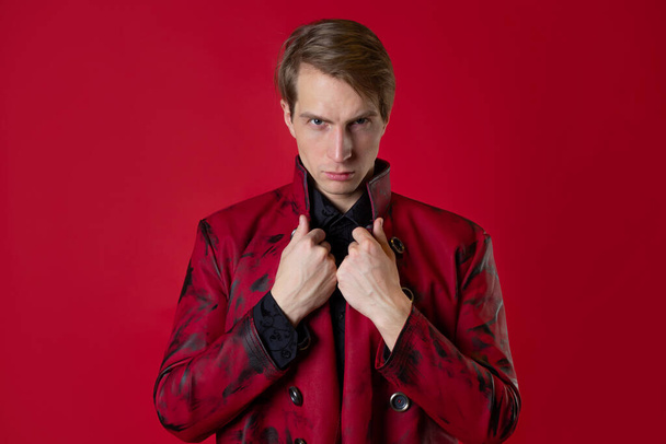 An outrageous young man in a daring red coat in a vintage noir style, - Фото, изображение
