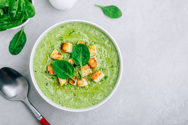 Green Cream Soup. Spinach broccoli creamy soup with croutons on gray stone background. Top view with copy space. - Фото, изображение