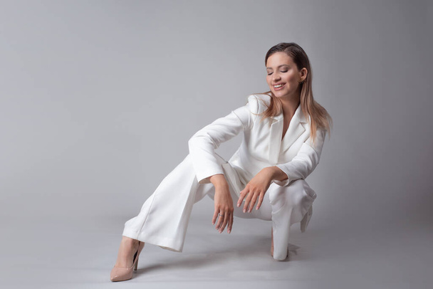 beautiful young woman in a trendy white suit and beige high-heeled shoes, - Fotografie, Obrázek