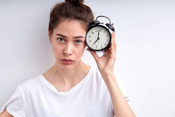 Photo portrait of young woman keeping alarm clock late for deadline stressed - Zdjęcie, obraz