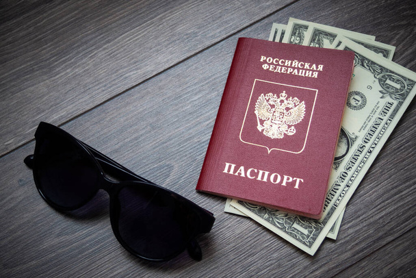 Ξένο διαβατήριο και δολάρια σε ξύλινο φόντο. Φωτογραφίες εγγράφων και τραπεζογραμματίων. - Φωτογραφία, εικόνα
