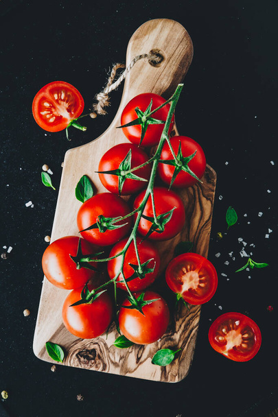 Tomatoes. Sweet ripe organic cherry tomatoes on a branch on wooden cutting board. - Fotoğraf, Görsel
